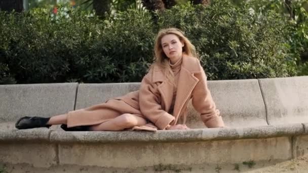 Romântico menina loira elegante sensualmente olhando na câmera deitada no banco no parque da cidade
 - Filmagem, Vídeo