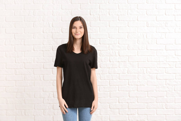 Woman in stylish t-shirt on white brick background - Foto, afbeelding