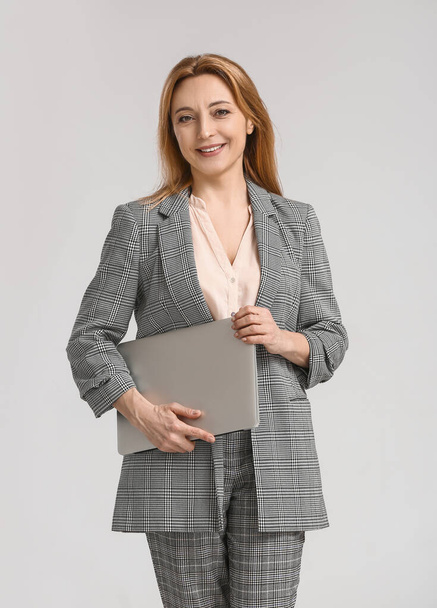 Portrait of stylish businesswoman with laptop on light background - Foto, afbeelding