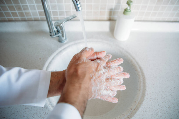 Mies pesee kädet kunnolla saippualla, joka on suojattu Coronavirus 2019-nCoV-pandemiainfektiolta. Lääkäri näyttää, miten pestä kädet kunnolla
. - Valokuva, kuva