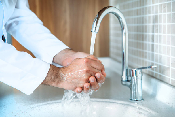 Muž řádně myje ruce mýdlem, aby byl chráněn proti pandemické infekci Coronavirem 2019-nCoV. Doktor ukazuje, jak správně umýt ruce. - Fotografie, Obrázek