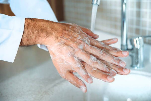 Muž řádně myje ruce mýdlem, aby byl chráněn proti pandemické infekci Coronavirem 2019-nCoV. Doktor ukazuje, jak správně umýt ruce. - Fotografie, Obrázek
