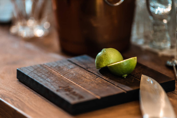 Halved fresh lime on a cutting board with a silver bucket on the background - Foto, imagen