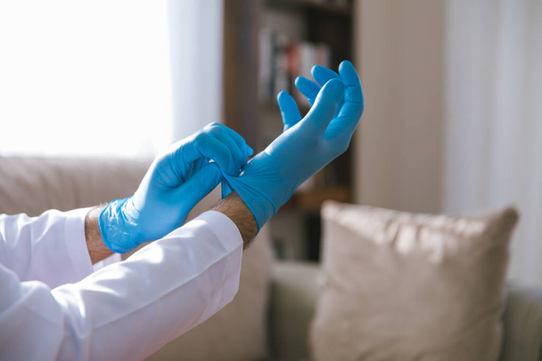 Covid-19 、 2019-nCoVまたはコロナウイルスの拡散を停止するための滅菌手術用手袋を着用する医師. - 写真・画像