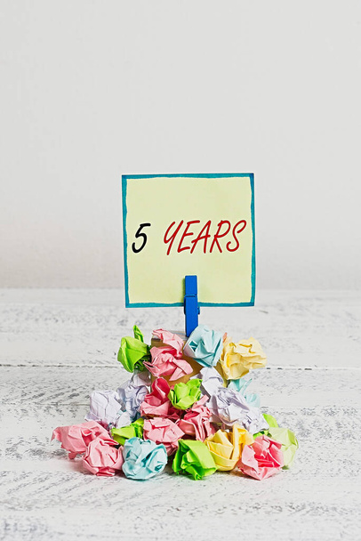 Conceptual hand writing showing 5 Years. Business photo showcasing Remembering or honoring special day for being 10 years in existence Reminder pile colored crumpled paper clothespin wooden space. - Photo, Image