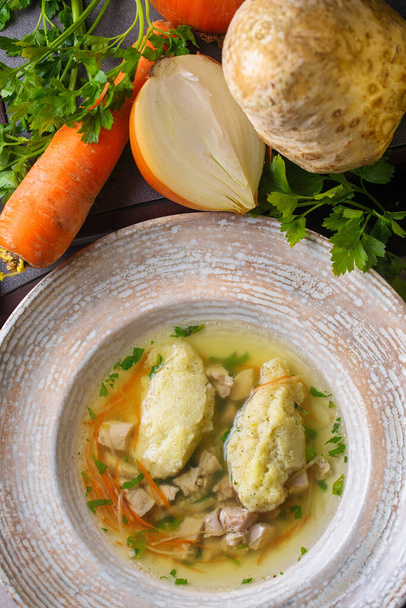 Sopa con eneldo, raíz de apio, zanahorias, repollo y patatas.Soup en un tazón blanco. Junto al tazón se cortan las papas, zanahorias y eneldo.
. - Foto, imagen