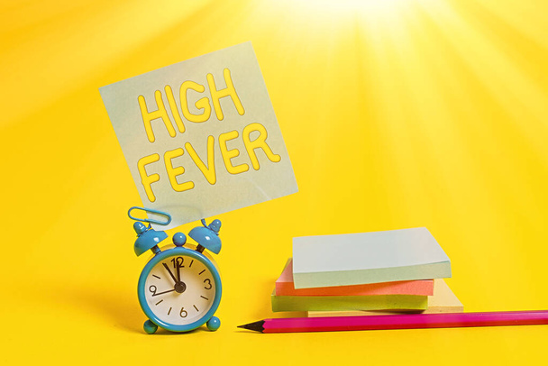 Text sign showing High Fever. Conceptual photo medical condition which the body temperature higher than usual Alarm clock blank pencil sticky note stacked notepads colored background. - Photo, Image
