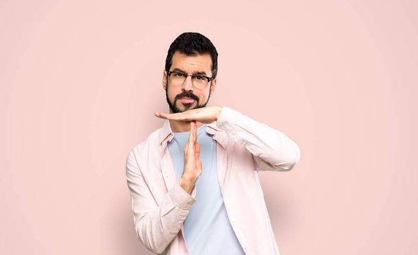 Handsome man with beard making time out gesture over isolated pink background - Photo, Image