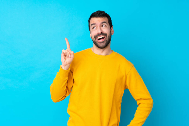 Young caucasian man over isolated blue background intending to realizes the solution while lifting a finger up - Photo, Image