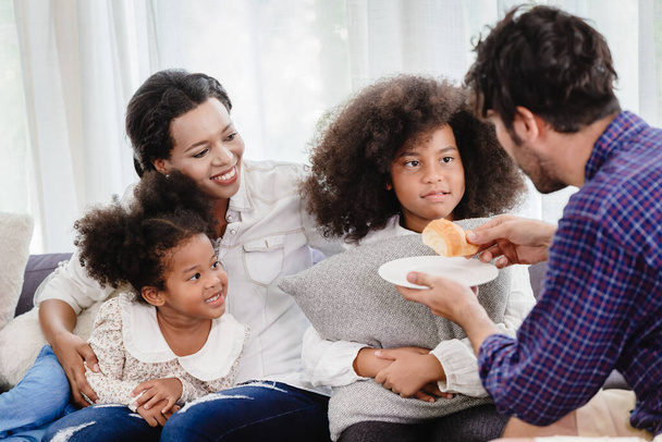 Домашняя счастливая семья, живущая вместе в гостиной отец мать играет с дочерью микс расы
. - Фото, изображение