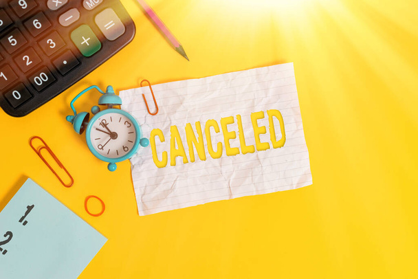 Text sign showing Canceled. Conceptual photo to decide not to conduct or perform something planned or expected Alarm clock clips note rubber band calculator pencil colored background. - Photo, Image