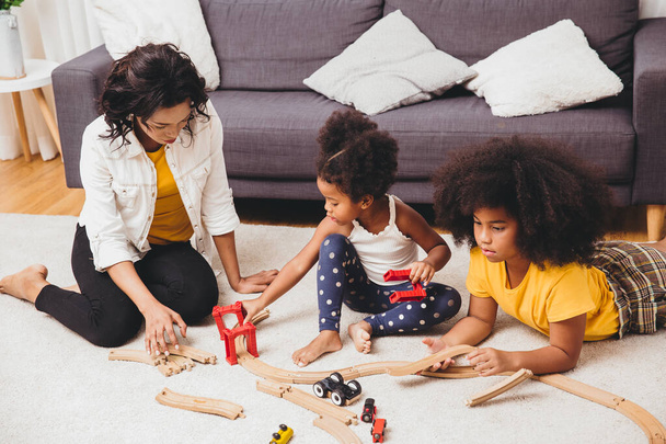 Matka rodzic bawiący się z dziećmi uczy się rozwiązywać zagadki zabawki w domu. Niania szuka lub opieki nad dziećmi w salonie czarnych ludzi. - Zdjęcie, obraz