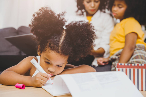 American Black przedszkola córka dzieci odrabianie lekcji nauki z siostrą mieszkających razem w domu. - Zdjęcie, obraz
