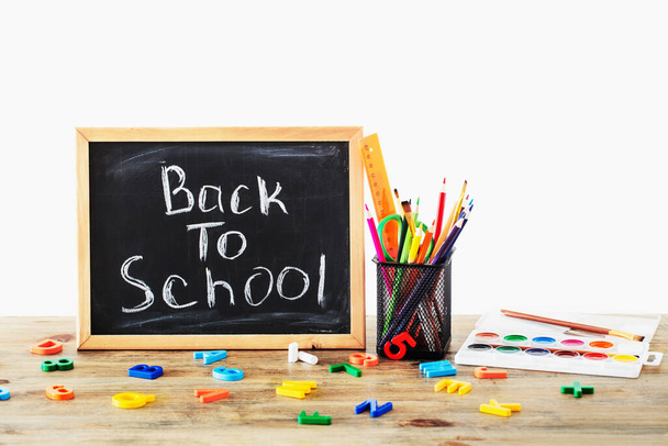 chalkboard with text and school supplies on wooden table, back to school concept - Φωτογραφία, εικόνα