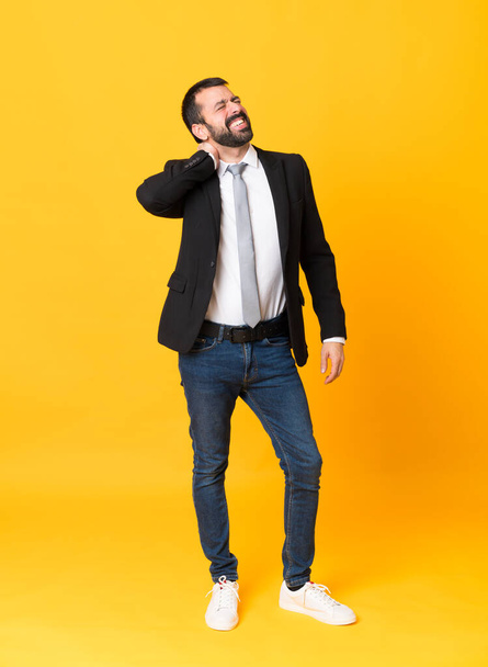 Full-length shot of business man over isolated yellow background with neckache - Foto, afbeelding