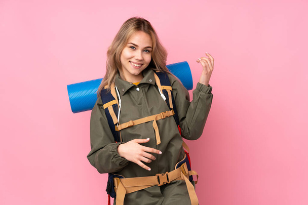 nastolatek rosyjski alpinista dziewczyna z a Duży plecak izolowane na różowy tło co gitara gest - Zdjęcie, obraz