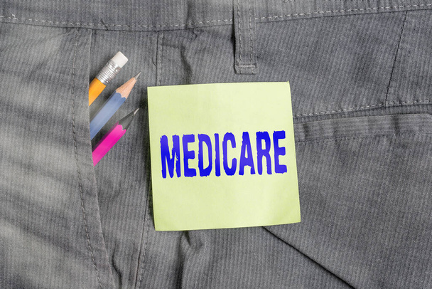 Escribiendo una nota que muestra Medicare. Foto de negocios que muestra el plan del gobierno federal en EE.UU. para pagar cierto hospital Equipo de escritura y papel verde en el bolsillo de los pantalones
. - Foto, imagen