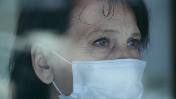 Sad woman in face mask behind window - Felvétel, videó
