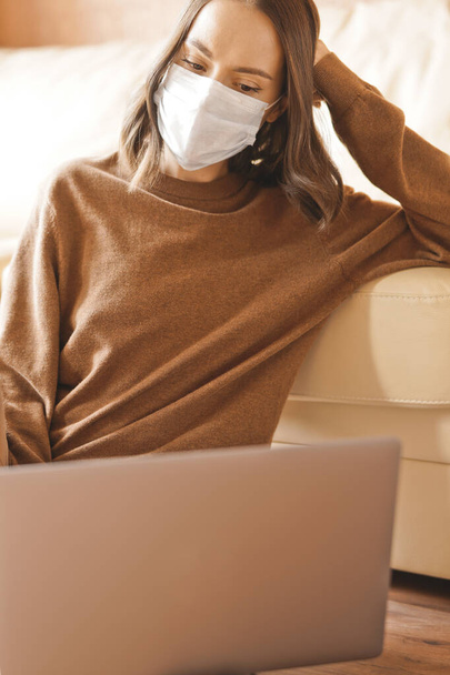 Lifestyle portrait of young lady working at notebook with mask. Woman concept for alternative office freelance. Stay home. Coronavirus. Quarantine. Online training education and freelance work. Coronavirus pandemic in the world - Fotografie, Obrázek