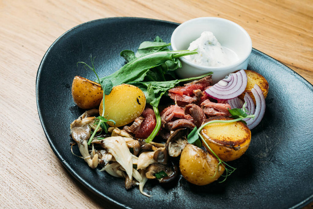 nationale Russische schotel van rundvlees stroganoff van varkensvlees, gekookte aardappelen, champignons en saus op een bord in een restaurant - Foto, afbeelding