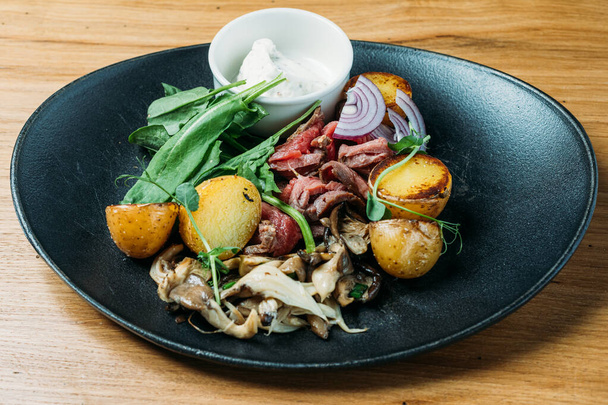 nationale Russische schotel van rundvlees stroganoff van varkensvlees, gekookte aardappelen, champignons en saus op een bord in een restaurant - Foto, afbeelding
