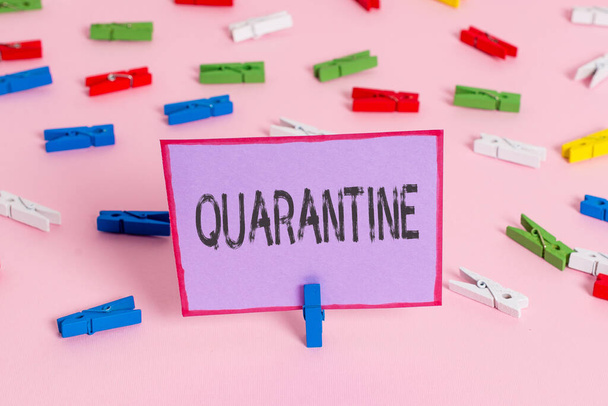 Writing note showing Quarantine. Business photo showcasing restraint upon activities of individuals or transport of goods Colored clothespin papers empty reminder pink floor office pin. - Fotó, kép