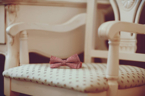 A pink bow tie is on top of a chair in classics style - Photo, Image