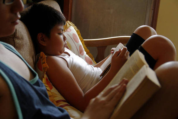 Fénykép fiatal filippínó fiúk olvasni könyveket tölteni az időt a zárlat miatt Covid 19 vírus kitörése. - Fotó, kép