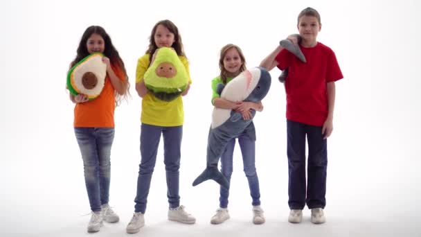 Um grupo de crianças adolescentes está segurando brinquedos macios em suas mãos, olhando para a câmera e sorrindo. Estúdio. Dia de Proteção de Crianças. Três meninas e um menino plano global
. - Filmagem, Vídeo
