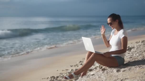 Urocza młoda kobieta w okularach przeciwsłonecznych rozmawia przez komunikację wideo - Materiał filmowy, wideo