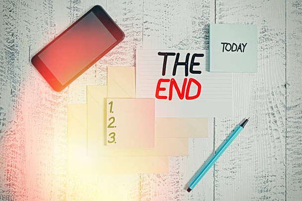 Word writing text The End. Business concept for Final part of play relationship event movie act Finish Conclusion Envelopes marker ruled paper smartphone sheet note pads wooden background. - Photo, Image