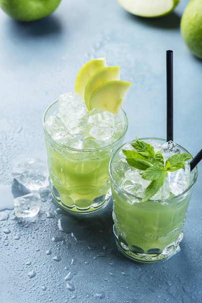 Green cocktail with ice and mint. Bar concept. Apple mojito with mint and ice on the blue background, selective focus image - Фото, изображение
