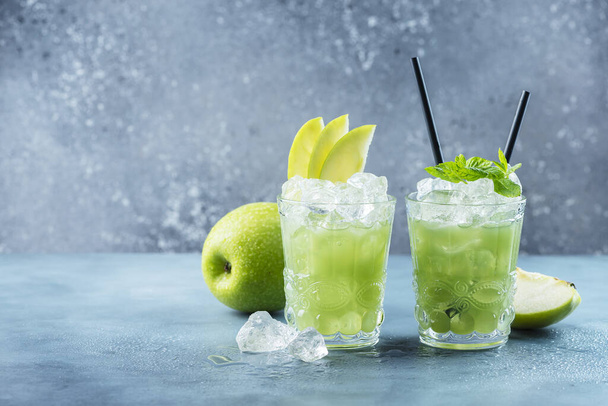 Green cocktail with ice and mint. Bar concept. Apple mojito with mint and ice on the blue background, selective focus image - 写真・画像