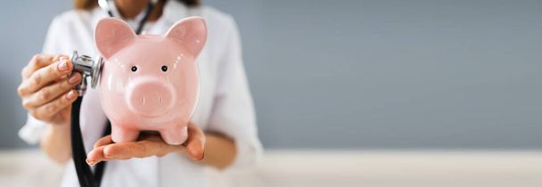 Doctor Health Checking Piggy Bank With Money Inside - Foto, imagen