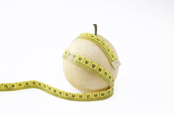 Ripe chinese pear for alternative diet illustration with tailor measuring tape isolated on white background - Photo, Image