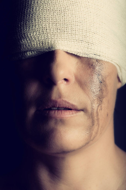 Konzeptfoto einer verletzten Frau, die weint und einen Verband um den Kopf trägt - Foto, Bild