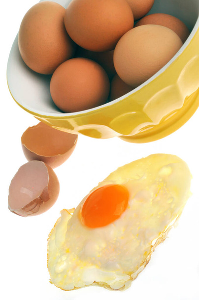 Gebratenes Ei mit Schüssel mit frischen Eiern in Nahaufnahme auf weißem Hintergrund - Foto, Bild