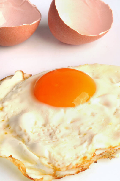 Huevo frito con cáscaras de huevo de cerca sobre fondo blanco
 - Foto, imagen