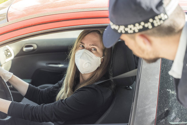 Coronavirus. A police medical technician in full protective gear collects a sample from a young woman sitting inside her car. Coronavirus mobile testing unit. Isolated. Quarantine.  - 写真・画像