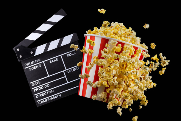 Flying popcorn and film clapper board isolated on black background - Zdjęcie, obraz