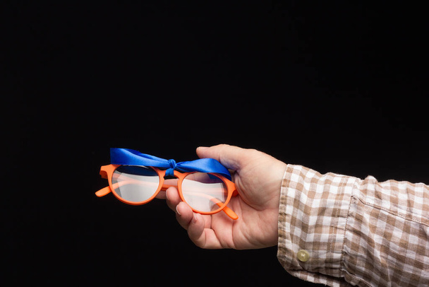Gözlüklerde görsel sağlık, görüş düzeltmesi için gözlük, siyah arka planda renkli tasarım gözlük. Yetişkin birinin elinde renkli lensler. Gözlük merceğindeki düzeltme. - Fotoğraf, Görsel