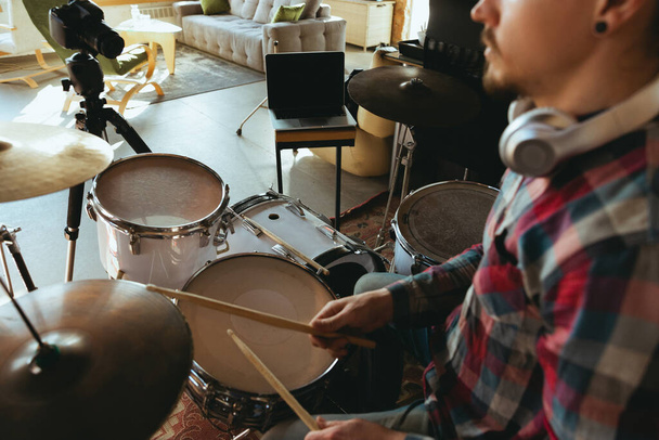 Caucasian musician playing drumms during online concert with the band at home isolated and quarantined, inspired improvising, close up - 写真・画像
