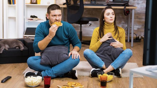 Disappointed couple sitting on the floor while watching sport - Photo, Image
