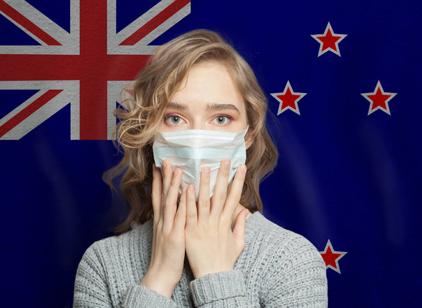 Verängstigte Frau in medizinischer Maske auf neuseeländischem Flaggenhintergrund. Grippeepidemie und häusliche Gewalt - Foto, Bild