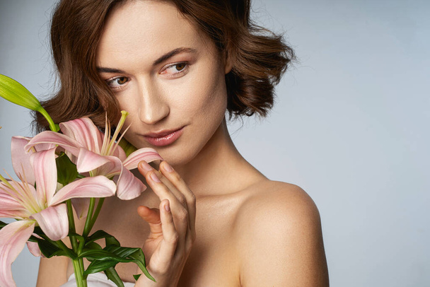 Smiling young woman smelling fresh cut flowers - Photo, Image