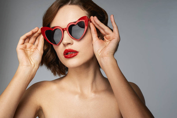 Carefree woman with red lipstick in heart-shaped sunglesses - Foto, immagini