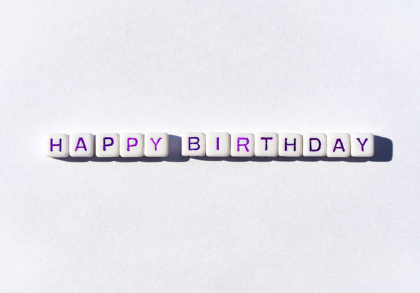 Boldog születésnapot képeslap kockákkal, lila betűkkel, fehér alapon - Fotó, kép