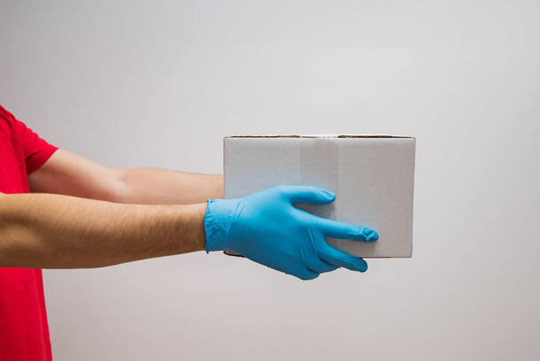 Delivery man holding cardboard boxes in protective rubber gloves. - Fotoğraf, Görsel