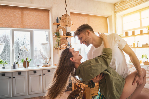 Positive delighted loving couple dancing in the kitchen - Фото, зображення
