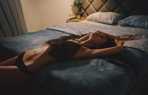 La fille nue se trouve sur le lit, une lumière jaune étouffée dans la chambre
 - Photo, image